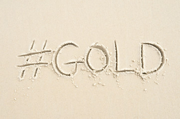 Hashtag social media message for gold written in sand on the beach in Rio de Janeiro, Brazil