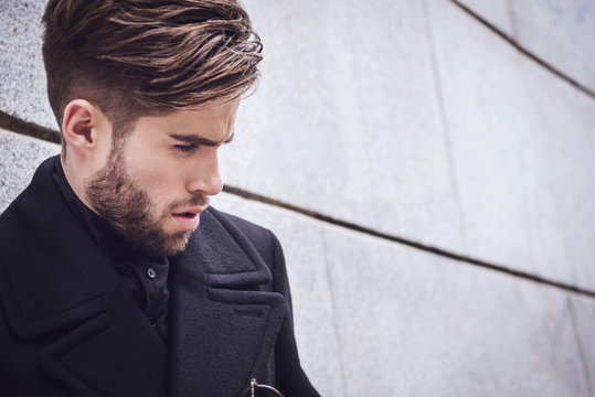 Young handsome trendy man with coat posing on stairs