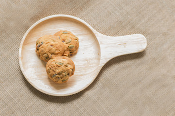 Oat cookies with pumpkin seeds and raisin on a wooden plate.
