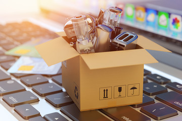 E-commerce, online shopping, internet purchases and goods delivery concept, cardboard box package with household and kitchen appliances on computer laptop keyboard