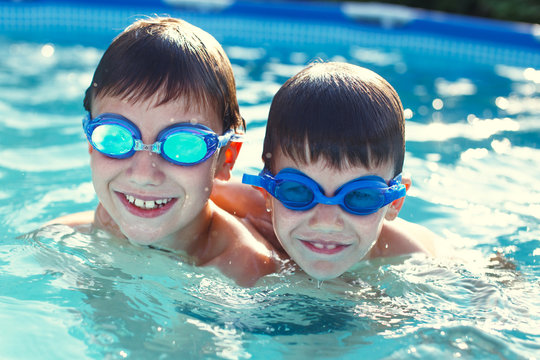 Happy little kids in goggles smile in pool
