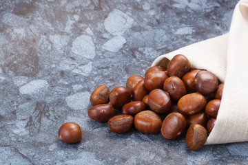 Horizontal image of a pile of chestnuts on stone texture floor with copy space