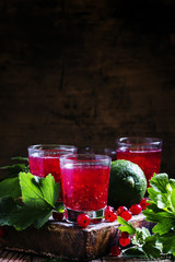Lime-currant red cocktail on a dark wooden background, selective
