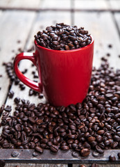Coffee beans and red coffee cup on wooden background. Drink
