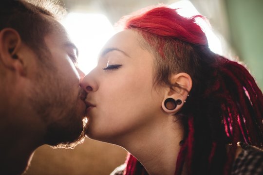 Romantic hipster couple kissing at home