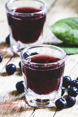 Homemade liqueur from aronia, fresh berries on a vintage wooden