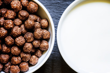 Breakfast concept, cereals balls and milk, dark background, top