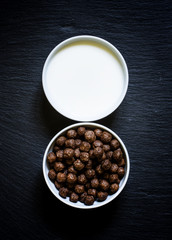 Breakfast concept, cereals balls and milk, dark background, top