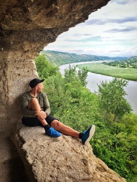 man sitting on the edge of cave rock monastery