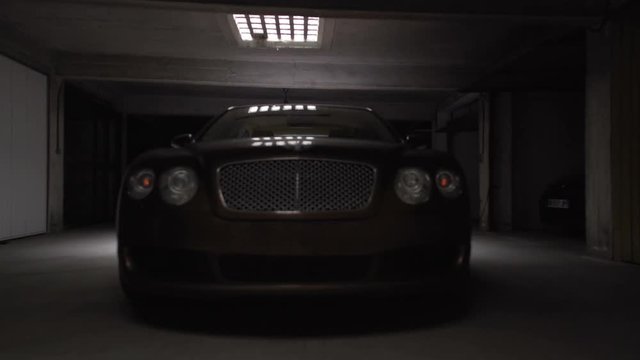 Professional driver testing new expensive car in garage, switching on headlights