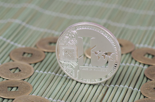 Silver-plated Litecoin on a wooden tablecloth. Selective focus.