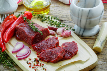 Beef tenderloin on a cutting board. Fresh raw meat for cooking dinner. Condiments and spices on the table
