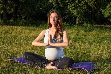 healthy pregnant woman doing yoga in nature outdoors