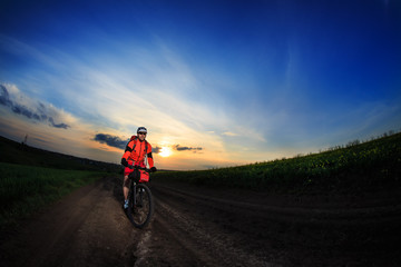 Fototapeta premium Mountain bikeer rides on the trail against beautiful sunset