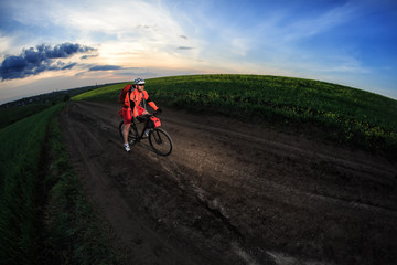 Fototapeta premium Mountain bikeer rides on the trail against beautiful sunset