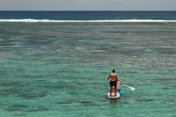 Young people riding board with an oar. Lagoon Hermitage, Reunion