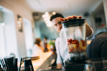 Barman preparing a pineapple and strawberry cocktail