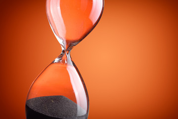 Closeup hourglass on orange background