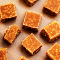 Sweet food - caramel cubes over baking paper top view