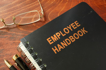 Employee handbook on a wooden table and glasses. - obrazy, fototapety, plakaty