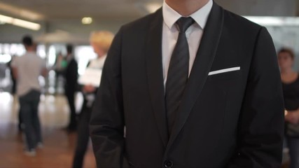 Man in business suit waiting for arrivals in airport hall, travel agent, tourism