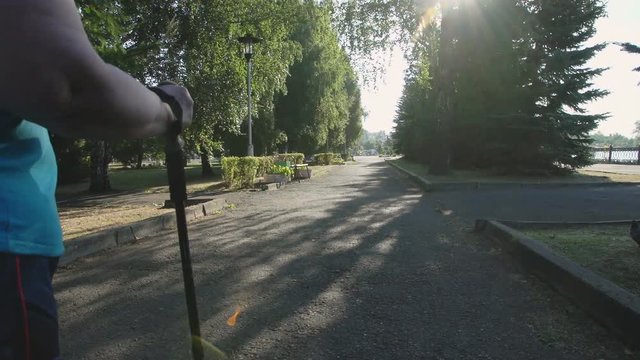 A woman walks through the Park with sticks for Nordic walking Sunny summer morning.
