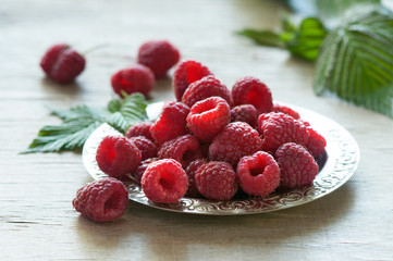 Ripe sweet raspberries in bowl on wooden table