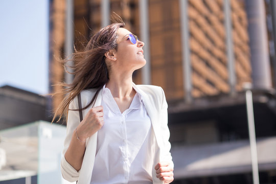 Businesswoman with windy hair looking up in the street