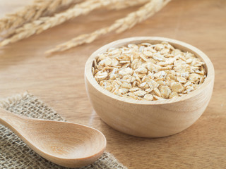 Wheat flakes in wooden bowl on wooden background - Raw food ingredients