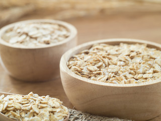 Wheat flakes in wooden bowl on wooden background - Raw food ingredients