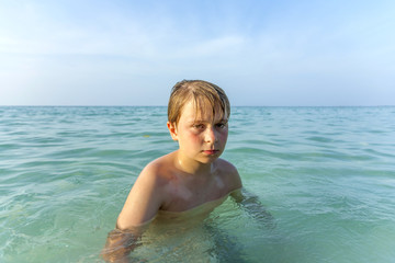 Fototapeta na wymiar angry young boy walking in the ocean at the beach