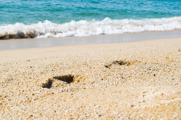 Footsteps on the sand beach, sea on background, seashore
