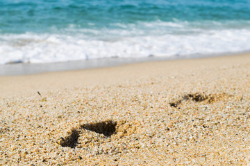 Footsteps on the sand beach, sea on background, seashore
