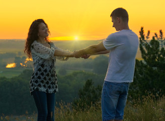 romantic couple holding hands at sunset on outdoor, beautiful landscape and bright yellow sky, love tenderness concept, young adult people