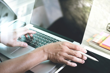 Designer hand working with laptop computer on wooden desk as res