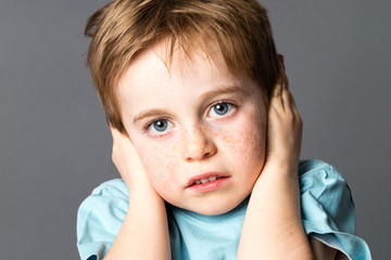 scared young boy suffering from domestic violence covering his ears