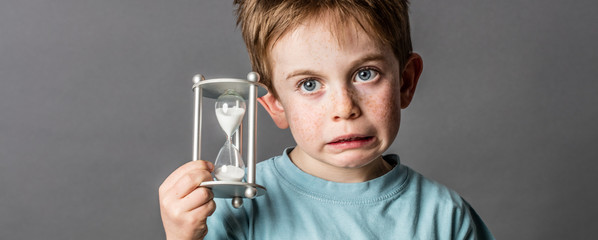 little boy with questioning eyes holding a scary egg timer