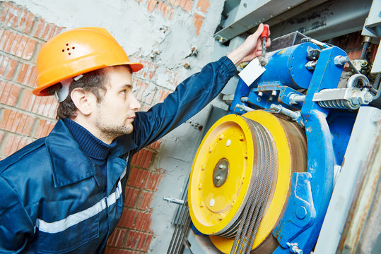 machinist worker adjusting elevator mechanism of lift