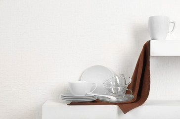 Set of tableware with napkin on shelf against white wall background