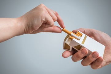 Hand is taking cigarette from cigarette pack an accepting an offer.