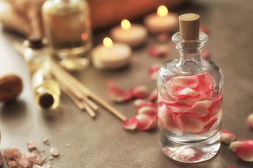 Bottle with rose petals on grey background