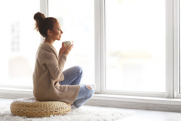 Beautiful African American girl drinking coffee at home