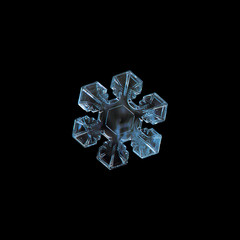 Snowflake isolated on black background. This is macro photo of real snow crystal with six short, broad arms and good symmetry.