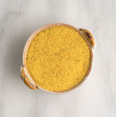 Chicken flavored bouillon in a small dish on a gray marble cutting board.