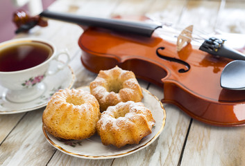 Coffee with cupcakes and violin on the wooden table 