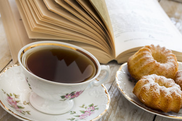 Coffee with cupcakes and book on the wooden table