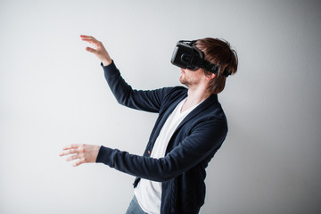 Handsome man wearing virtual reality glasses isolated on a gray background