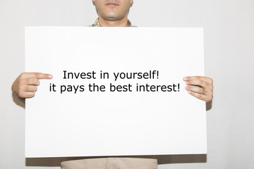 Invest in yourself, it pays the best interest - man holding a signboard with a text on it