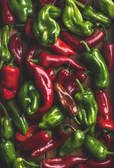 Background of colorful red and green bell peppers over wooden backdrop, top view
