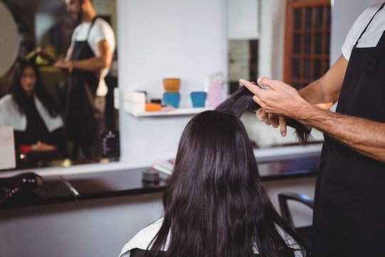 Hairdresser trimming hair of female customer in salon